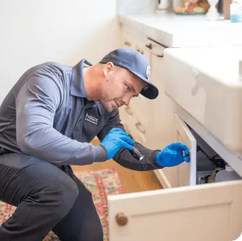 Hawx technician inspecting and treating under kitchen cabinets